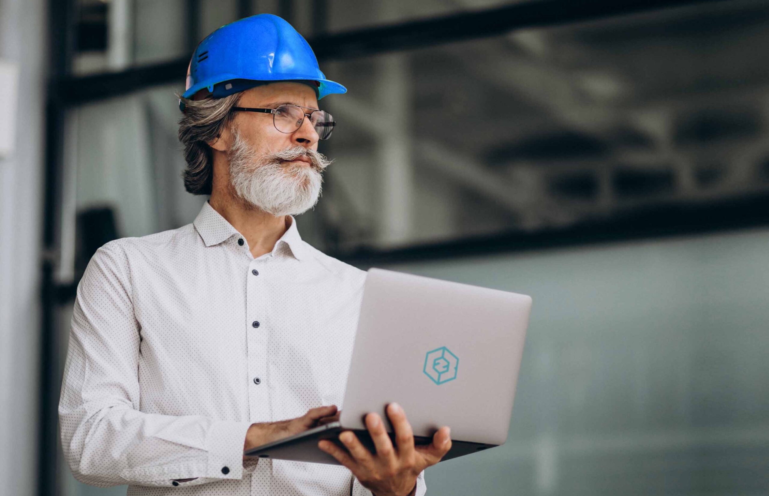 Gerente de proyecto gestionando plazos con C2B Gerente de proyecto de edad media con casco sujetando computador portátil